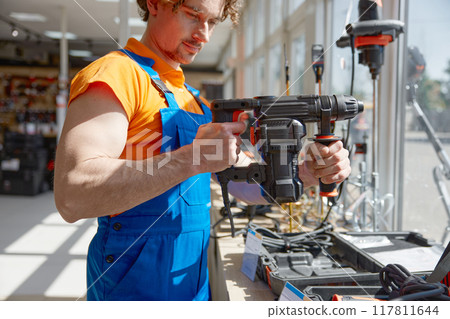Serious hardware shopkeeper holding perforator electric manual tool 117811644