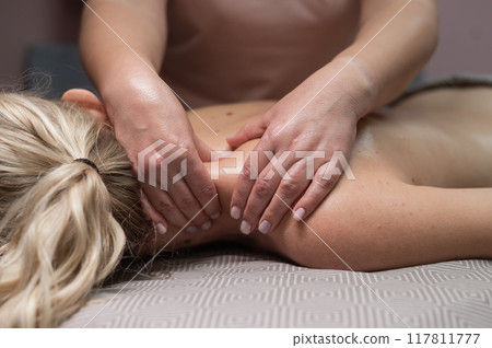 A woman gives a manual massage to a client. Close-up. A woman gives a manual massage to a client. Close-up. 117811777