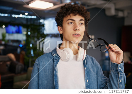 Portrait of smiling teenage boy standing in office 117811787