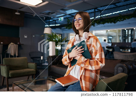 Attractive teenage girl reading work book in comfortable modern office Attractive teenage girl reading work book in comfortable modern office 117811798