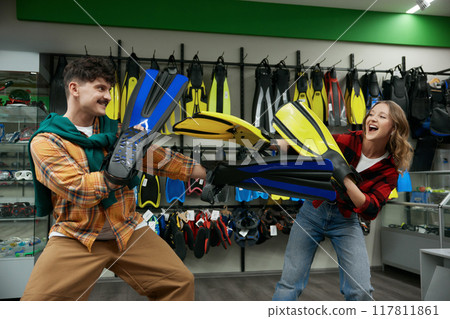 Young joyful man and woman couple fighting flippers at shop store 117811861