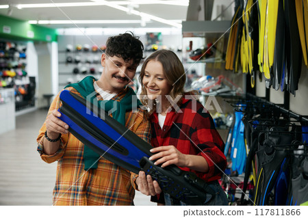 Young man and woman choosing diving tools looking for flippers at shop 117811866