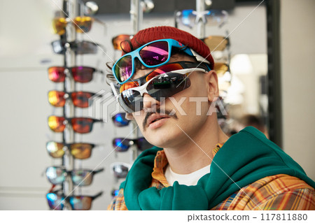 Funny hipster man customer wearing different kinds of sportive sunglasses Funny hipster man customer wearing different kinds of sportive sunglasses 117811880
