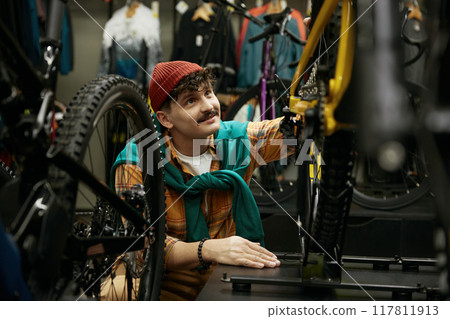 Hipster man selecting new mountain bike in shop Hipster man selecting new mountain bike in shop 117811913