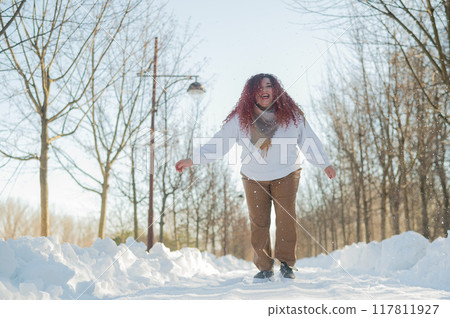 Smiling chubby redhead woman running in park in winter. Smiling chubby redhead woman running in park in winter. 117811927