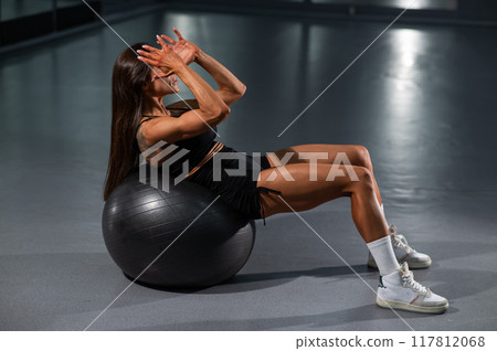 Caucasian woman doing abdominal exercise on fitball.  117812068