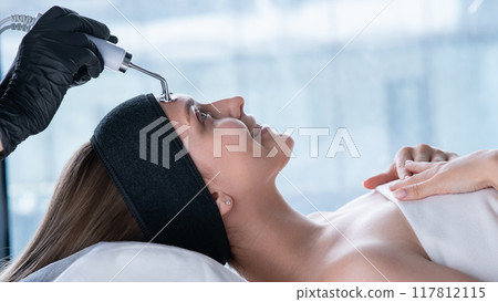 Young caucasian woman on microcurrent therapy procedure. Beautician's office. Young caucasian woman on microcurrent therapy procedure. Beautician's office. 117812115