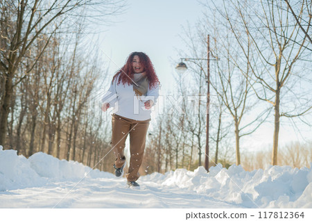 Smiling chubby redhead woman running in park in winter. Smiling chubby redhead woman running in park in winter. 117812364