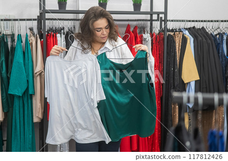 Caucasian fat woman chooses clothes. Plus size store. Caucasian fat woman chooses clothes. Plus size store. 117812426