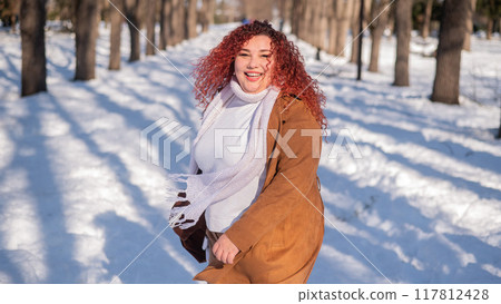Portrait of an excited red-haired curly fat woman in the park in winter. Portrait of an excited red-haired curly fat woman in the park in winter. 117812428