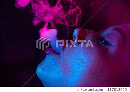 Close up portrait of asian woman with short hair smoking in neon light.  117812633