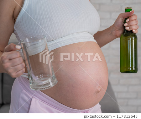 Pregnant woman holding glass and bottle of beer.  117812643