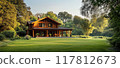 Beautiful Rustic Wooden Cabin in a Lush Green Forest with Sunlight Filtering Through the Trees 117812673