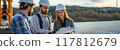 Engineers Discussing Solar Panel Installation on a Rooftop with Scenic Background 117812679