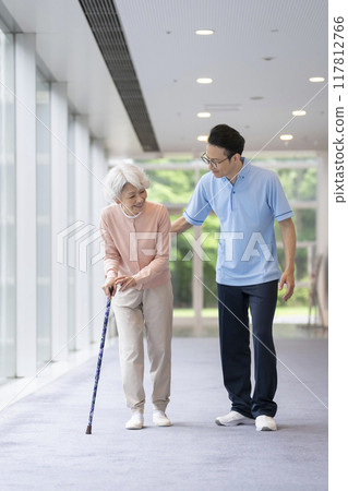 Senior woman walking with a cane and care staff Senior woman walking with a cane and care staff 117812766