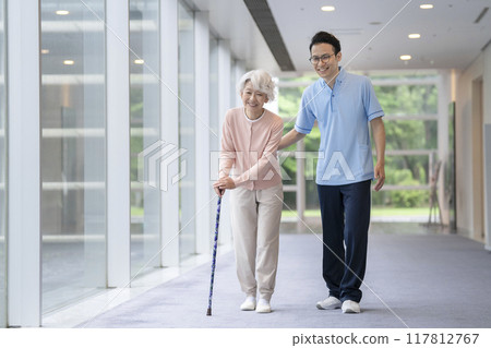 Senior woman and caregiver walking with a cane Senior woman and caregiver walking with a cane 117812767