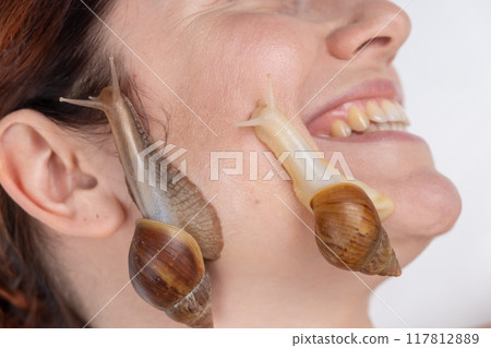 Beautiful caucasian smiling woman with snails on her face. Skin rejuvenation therapy. Beautiful caucasian smiling woman with snails on her face. Skin rejuvenation therapy. 117812889