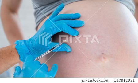 Doctor gives an injection in the stomach of a pregnant woman. Doctor gives an injection in the stomach of a pregnant woman. 117812951