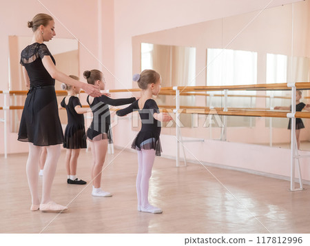 Children's ballet school. Caucasian woman teaching ballet to little girls.  117812996