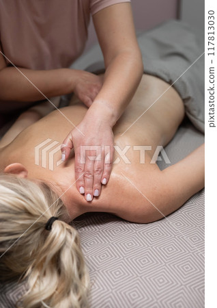 A woman undergoing a massage of the cervical-collar area. Vertical photo. A woman undergoing a massage of the cervical-collar area. Vertical photo. 117813030