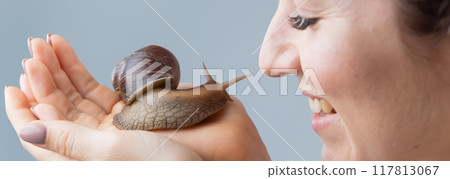 Closeup of a Caucasian woman holding a large snail. The use of shellfish in cosmetology. 117813067