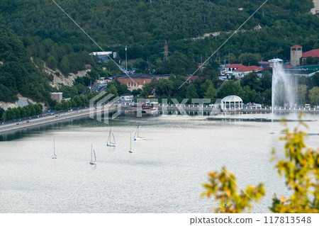 A peaceful and serene lakeside view featuring various boats and elegant fountains A peaceful and serene lakeside view featuring various boats and elegant fountains 117813548