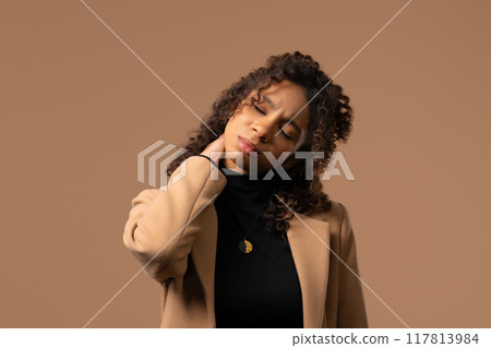 Tired teenager girl feeling pain in neck joint, massaging muscles, rubbing head. 117813984