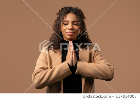 Believer teen girl praying,reads prayer, beige background.Hope, wish, gratitude 117814005