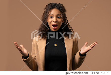 Amazed african american teenager girl expresses WOW. OMG. Impressed lady on beige. Great news 117814006
