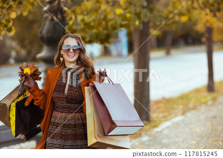 happy modern woman in orange trench coat with shopping bags happy modern woman in orange trench coat with shopping bags 117815245