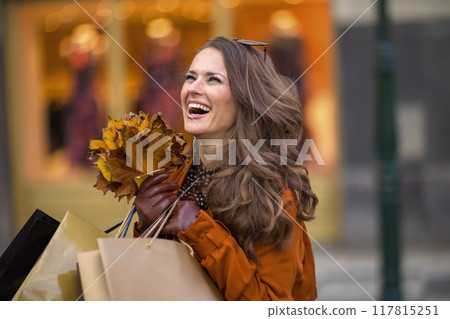 happy trendy female in orange trench coat with shopping bags happy trendy female in orange trench coat with shopping bags 117815251