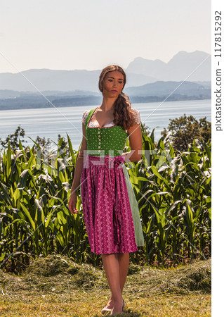 "Traditional beauty: woman in a dirndl in front of a mountain and lake landscape" "Traditional beauty: woman in a dirndl in front of a mountain and lake landscape" 117815292