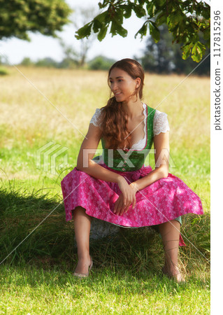 "Thoughtful woman in a dirndl in a meadow" 117815296