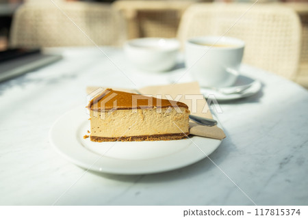 Tasty cheesecake with caramel and nuts served on white table. Classic New York cheesecake on a white concrete background, side view.  117815374