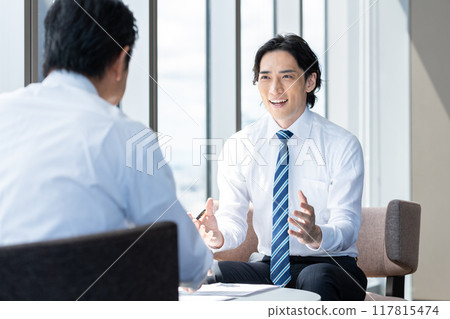 Businessmen having a meeting in an office. Photo courtesy of Tokyo Electronics College, Denpa Gakuen School Corporation. 117815474