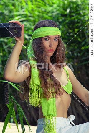 Boho style by the lake: young woman with green headscarf in summer outfit 117815850