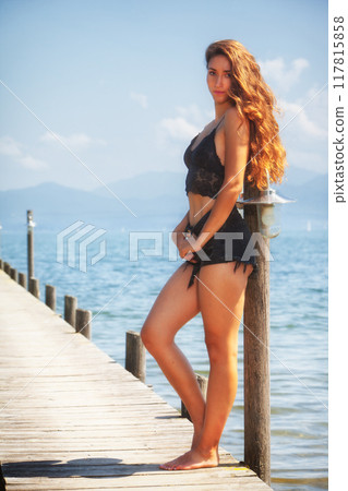 Sensual summer portrait of a young woman in black lace by the lake Sensual summer portrait of a young woman in black lace by the lake 117815858
