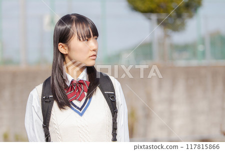 A high school girl in uniform standing in front of the schoolyard 117815866