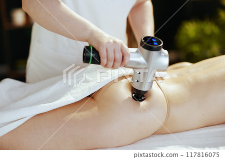Closeup on medical massage therapist massaging clients buttocks 117816075