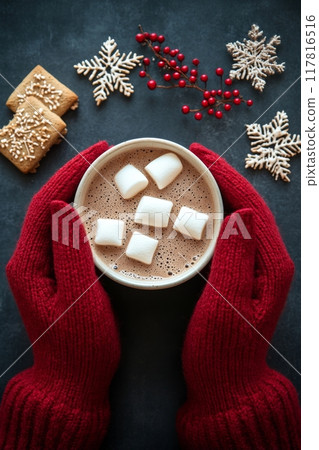 Warm holiday hot chocolate topped with marshmallows and cookies on a festive table 117816516