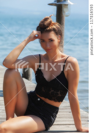Relaxed summer portrait: Woman in a black lace top by the lake Relaxed summer portrait: Woman in a black lace top by the lake 117816593