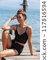 Sun-kissed: Woman in a black lace top enjoys the summer breeze by the lake 117816594