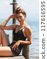 Elegance by the water: woman in a black lace outfit on a jetty by the lake 117816595