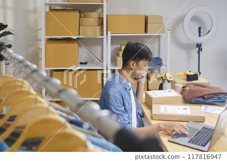 Young entrepreneur managing online clothing business Young entrepreneur managing online clothing business 117816947