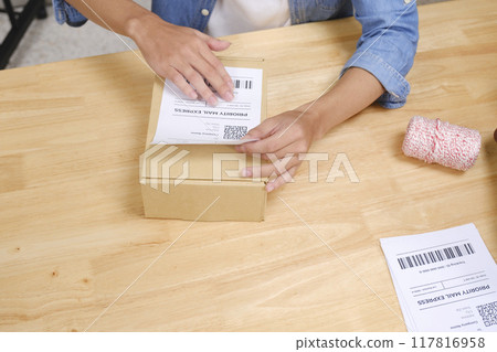 Asian man business owner scanning barcode on delivery parcel. 117816958