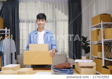 Portrait of a confident young online entrepreneur working from his home office, surrounded by clothing products and shipping boxes. 117816962