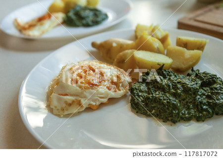 Fried egg with spinach and potatoes on a plate Fried egg with spinach and potatoes on a plate 117817072
