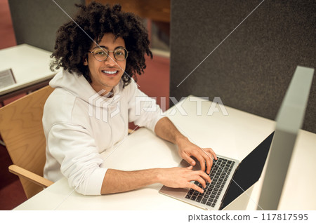 Man studying with computer preparing for exams in high school library Man studying with computer preparing for exams in high school library 117817595