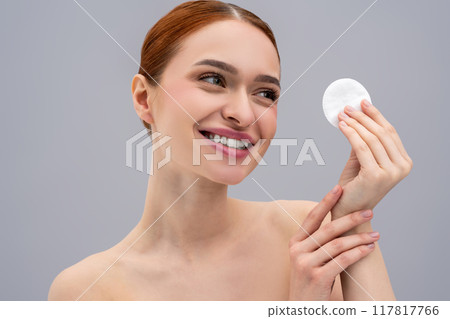Cute young woman cleaning her face with a sponge Cute young woman cleaning her face with a sponge 117817766