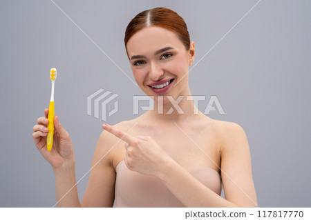 Happy young woman brushing teeth and looking enjoyed Happy young woman brushing teeth and looking enjoyed 117817770